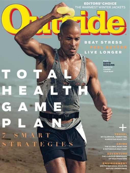 A muscular man running on the beach pours water on his head; he is sweaty, wearing shorts and a tank top, featured on the cover of Outside magazine.
