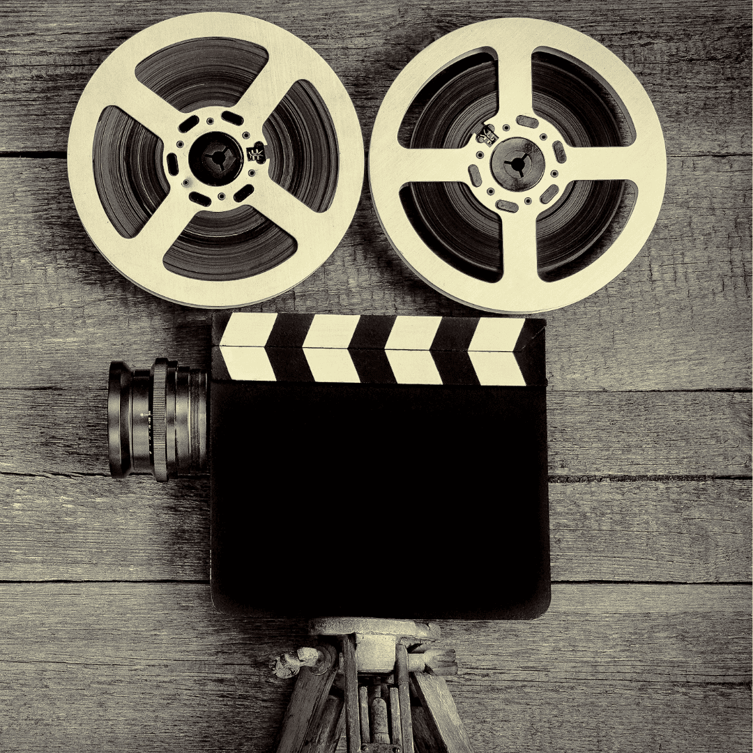 vintage film camera with two reels and a clapperboard on a wooden surface, viewed from above.