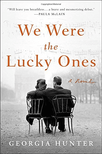two people sit close together on metal chairs, facing away, on the cover of the novel we were the lucky ones by georgia hunter.